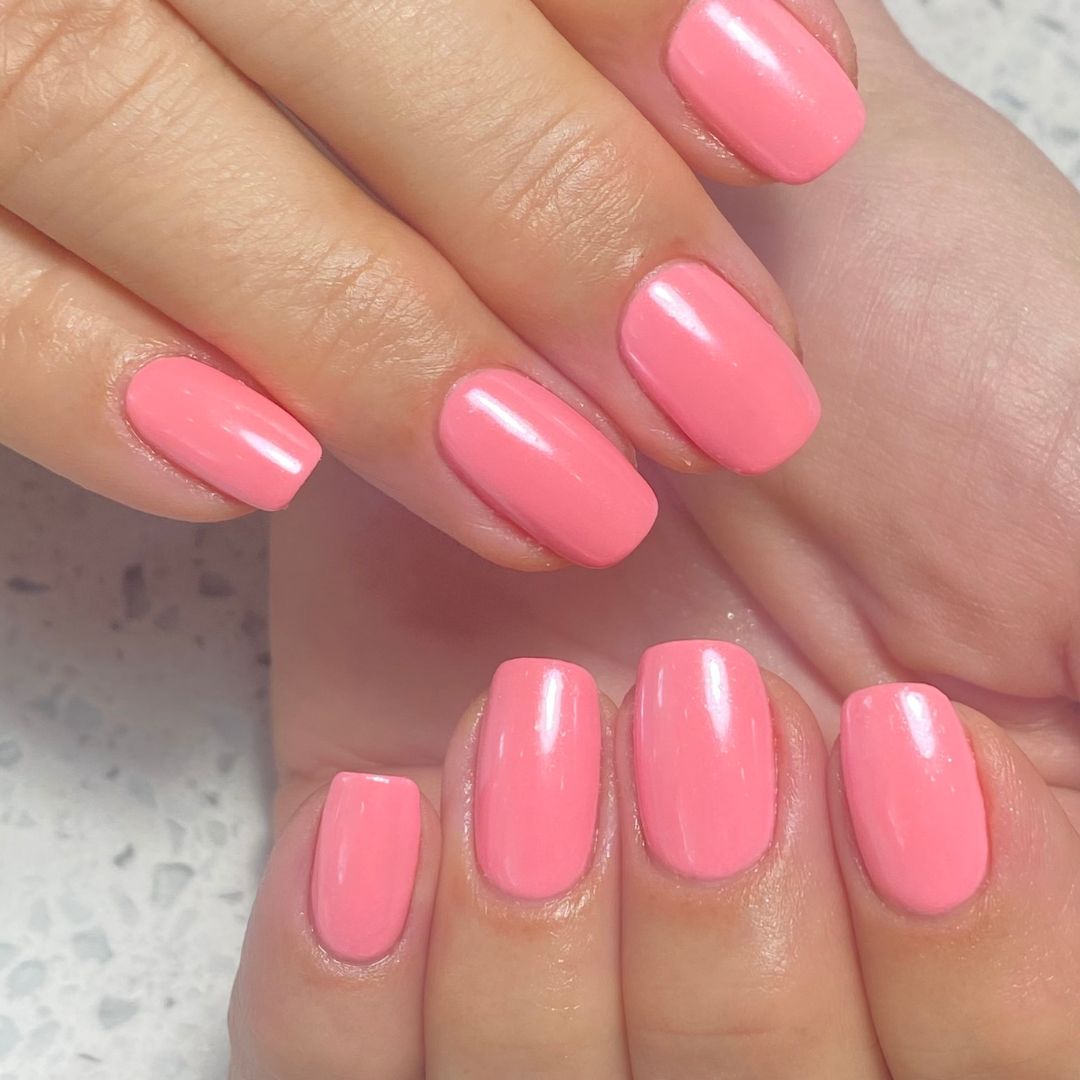 Bright bubblegum pink gel polish manicure with a smooth, glossy finish and clean cuticle work. Short to medium-length nails shaped square for a classic look.