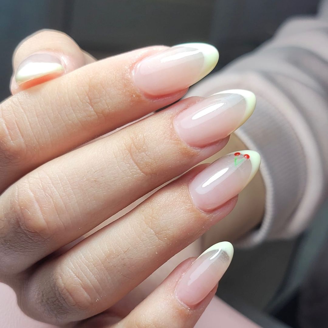 Minimalist French tip manicure with soft almond-shaped nails, featuring sheer pink gel polish and pale lemon-white tips.