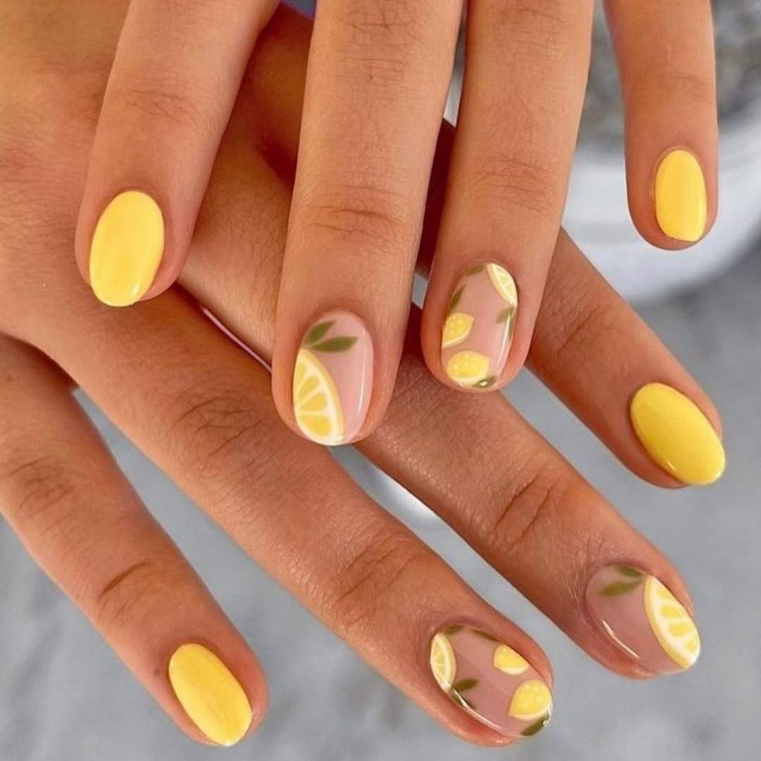 A bright and cheerful lemon-inspired manicure with a mix of glossy yellow nails and detailed citrus designs, perfect for adding a fresh, summery touch to any look.