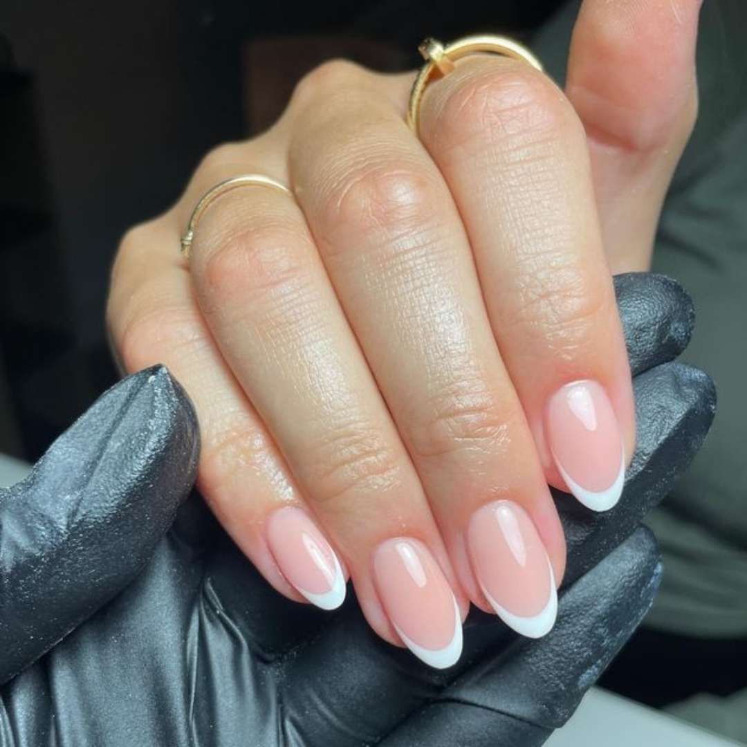 Polish application featuring a modern French manicure with almond-shaped nails, soft pink base, and crisp white tips for a chic and sophisticated style. Polish Application nails done at Casa D'Blanca Nails + Spa in Grimsby on the Lake.