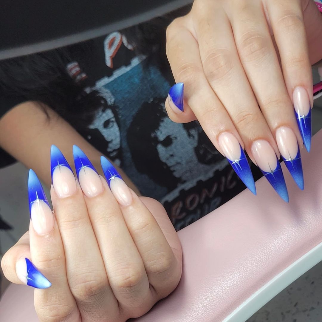 Long stiletto nail enhancements with blue ombré French tips and white starburst design, created at our Grimsby salon. 