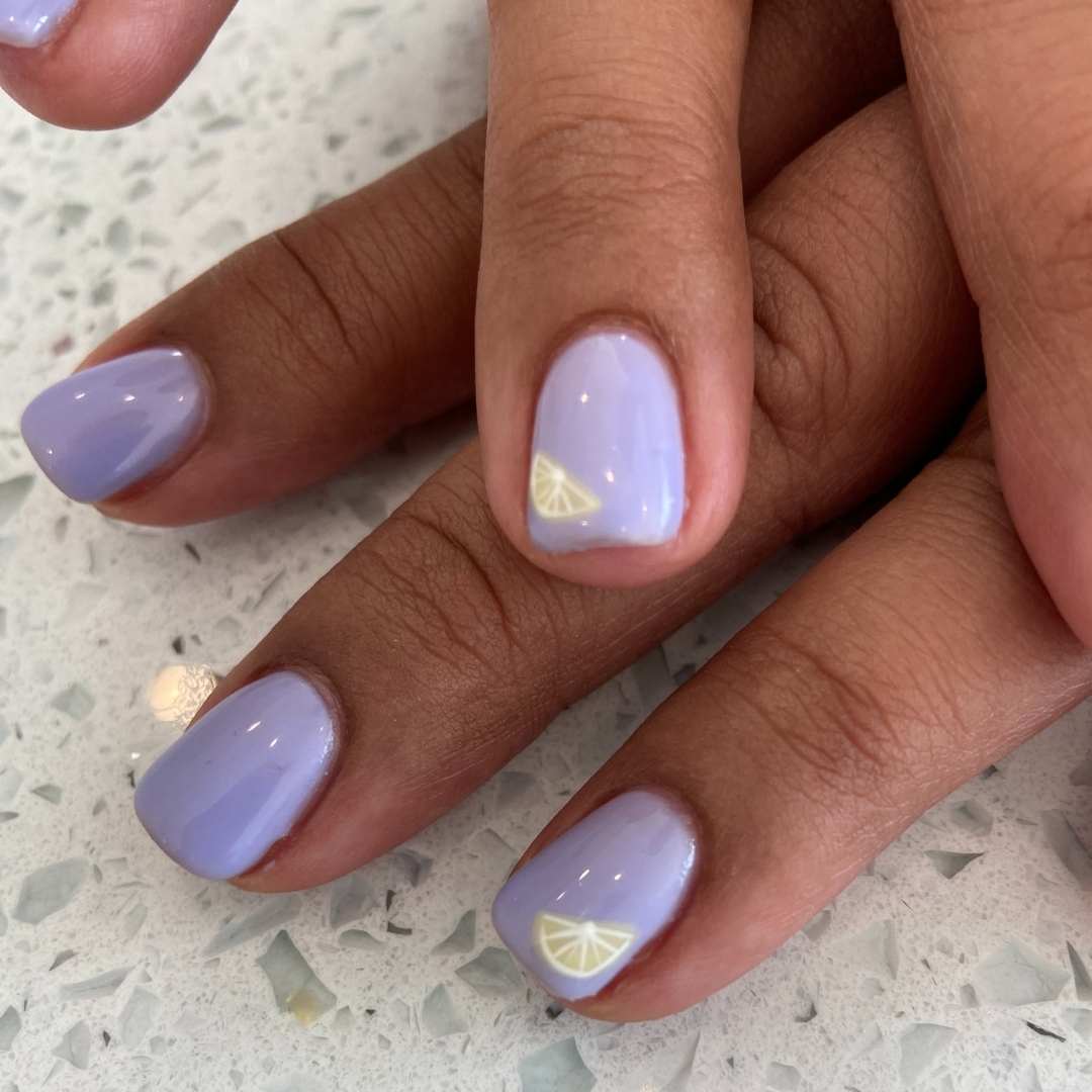 Soft pastel purple manicure with a minimalist lemon accent design, offering a fresh and subtle nail art option as part of our manicure services at Casa D'Blanca Nails + Spa in Grimsby on the Lake.