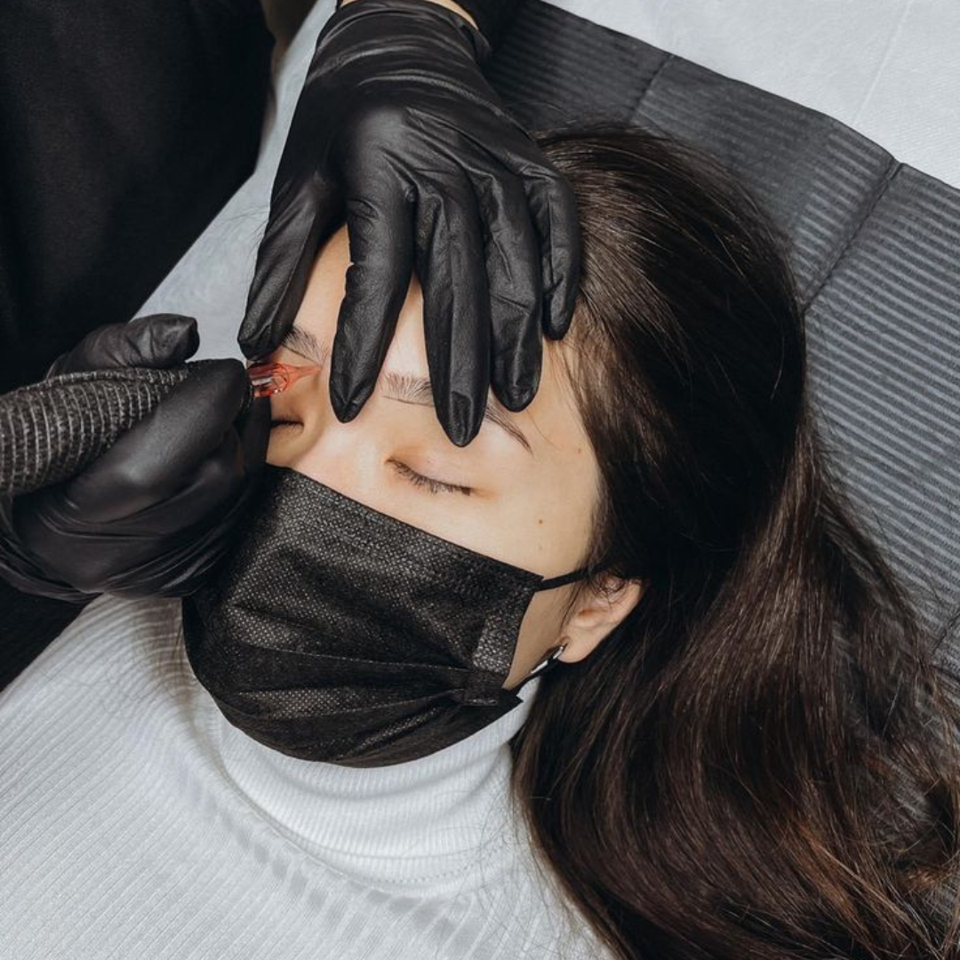 Close-up of a powder brow tattooing procedure, where a technician uses a machine to create soft, shaded eyebrows for a defined yet natural look.